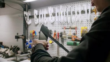 İşçi atölyede siyah yapıştırıcıyı alet koluna sarar. İşçi, bakım onarım görevi için sıkılaştırıcı yüzey güvenliğini sıkılaştırıyor