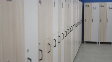 Soyunma odasında sıcak ahşap desenli numaralandırılmış dolaplar var. Düzenli düzen, değişen alanı hoş karşılar