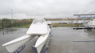 Elektrikli jet ski bulutlu bulutlu gökyüzünün altında ıslak otopark yüzeyinde duruyor. Rutubetli asfalt ve sessiz ışık dengesiz endüstriyel atmosfer yaratır