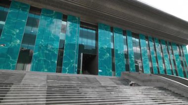 Geniş taş merdiven modern arenanın cam girişine çıkıyor. Turkuaz cephe, pencerelerde geometrik çizgiler oluşturan gün ışığını yansıtır