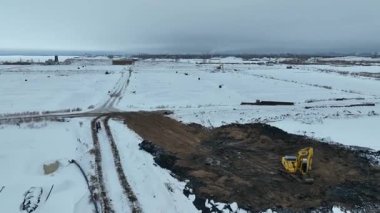 Kazıcı karlı araziyi kazıyor. Kare çizgilere bölünmüş halde. Ağır kazıcı karla kaplı araziyi ızgara benzeri çizgilerle yeniden şekillendiriyor