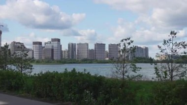 Sakin göl, yüksek modern binalarla dolu uzak megapolis siluetini yansıtır. Açık yaz atmosferi açık geniş duygular yaratır.