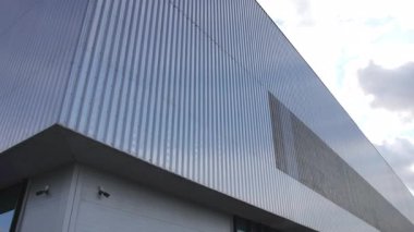Bükülmüş metalle kaplanmış sanayi binası katı geometri sergiliyor. Sönük renkler sanayi bölgesinin minimalist karakterini güçlendiriyor
