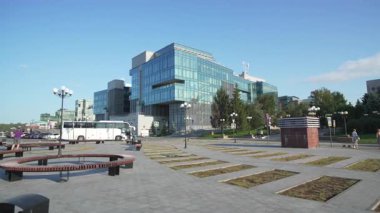 Şehir meydanının üzerinde cam cephe kuleleri olan modern iş merkezi. Yansıtıcı yüzeyler kurumsal ölçek ve berraklığı vurguluyor