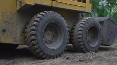 Kazıcı, yerleşim alanındaki ağır inşaat enkazlarını temizliyor. Mekanik hareket dağınık avluyu düzenli kentsel alana dönüştürür