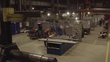 ALMATY, KAZAKHSTAN - 18 Ocak 2025: Kaynakçı çalışma bölgelerine bölünmüş geniş atölyedeki metal elementlerine katıldı. Keskin ışık hassasiyeti ve endüstriyel yoğunluğu vurguluyor