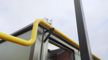 Gaz tesisinin dışındaki parlak sarı boru hattı yılanları. Temiz ve yapılandırılmış metal tüplerde organize enerji dağılımı vurgulandı