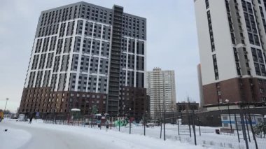 Çağdaş binalar, kentsel çevrenin dönüşümünü simgeleyen eski konut blokları arasında yükseliyor. Görsel ton dinamik görünür