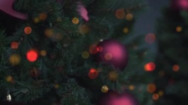 Arka planda bulanık altın çelenk ve Noel ağacında Noel topları var. Odaklanamayan bulanık bokeh ışıkları