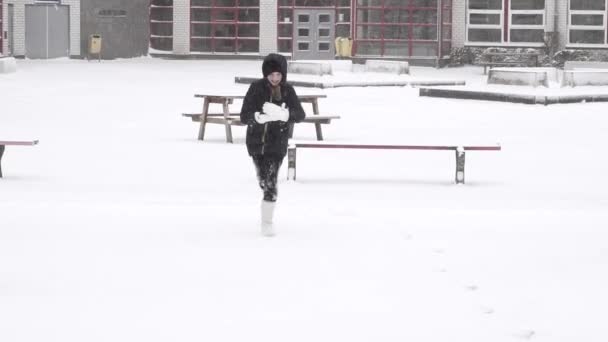 陽気な女の子は公園の散歩に雪玉を投げます 幸せな女の子は冬を楽しんで雪玉を楽しんでいます — ストック動画