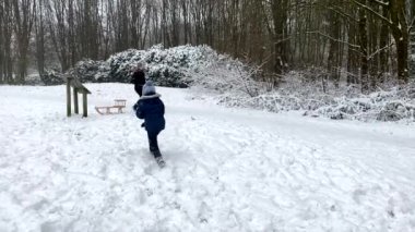 Mutlu aile kış parkında karla oynarken eğleniyor. 4K çözünürlüğü