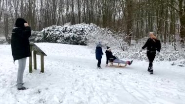 Mutlu aile kış parkında karla oynarken eğleniyor. 4K çözünürlüğü