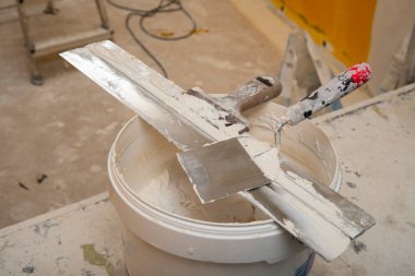 Kirli Spatula ve Kazıyıcı bir kova macunun üstünde. Yenileme ve inşaat işleri konsepti