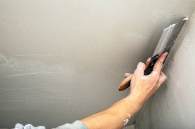 Müteahhit işçilerin el boşlukları tavanda macun sıva ile kaplanmış spatula ile hizalanır. Yenileme ve inşaat çalışmaları