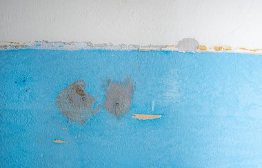 Eski tuğladan duvar, sıva soyulmuş. Tuğla işçiliğiyle yıpranmış. Duvar farklı renklerde boyanmış.. 