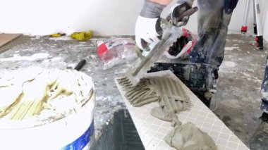  Seramik fayanslara çimento yapıştırıcısı sürüyorum seramik fayanslar yerleştiriliyor. İnşaat, yenileme, onarım...