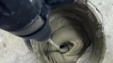 İnşaat alanındaki kovaya çimento karıştıran bir işçi.