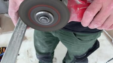 Metal profili kesen profesyonel inşaat işçisi. Tamirat sırasında metal profili öğütücüyle kesmek. Bir sürü sürtünme kıvılcımı