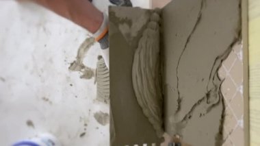 Tiler seramik fayansları yerleştirmek için yere yapıştırıcı sürüyor. İnşaat alanında fayans döşemek. Seçici odak, çokça kopyalama alanı