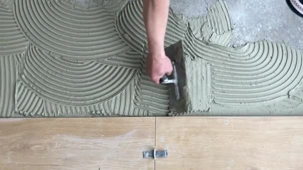 Ein Fliesenleger Trägt Klebstoff Auf Den Boden Auf Keramische Fliesen — Stockvideo