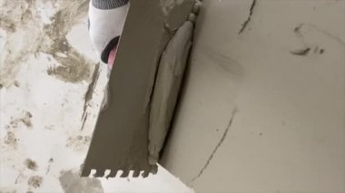 Tiler seramik fayansları yerleştirmek için yere yapıştırıcı sürüyor. İnşaat alanında fayans döşemek