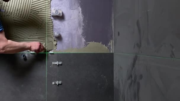 セラミック壁タイルをインストールします 修理改修作業で床にセラミックタイルをインストールするプロの建築家の労働者 — ストック動画