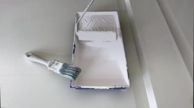 Beyaz boya ve fırça silindirli plastik boya tepsisi. Beyaz boya ve tepsiyle boya silindiri