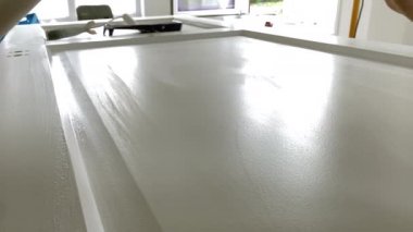 Boya fırçası yakın plan. İşyerindeki ressam ahşap kapıyı boya fırçasıyla beyaz boyayla boyuyor.