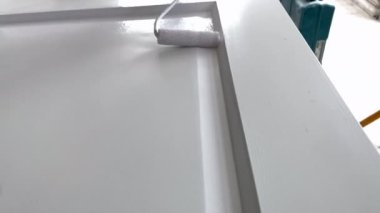 Boyacı kapanışı. İşyerindeki ressam ahşap kapıyı beyaz boyayla boyuyor.