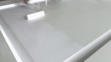 Boyacı kapanışı. İşyerindeki ressam ahşap kapıyı beyaz boyayla boyuyor. Profesyonel resim hizmetleri