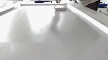 İşyerindeki ressam ahşap kapıyı beyaz boyayla boyuyor..