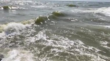 Su sıçratan deniz dalgaları ve köpükler kayalık kıyıya çarpıyor.