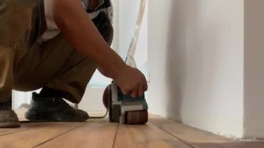 Marangoz parke döşemede onarım işi yapar. Tahta zemini öğütücüyle zımparalıyorum.
