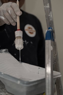 Eldivenli el, yuvarlak bir fırça kullanarak kapı çerçevesini boyuyor..
