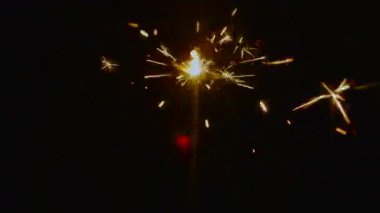 Parlak altın kıvılcımlar saçan yanan kıvılcımlar her yöne doğru uçuyor. Neşeli, ılık, ışıltılı arka plan. Yılbaşı ve Noel görselleri için mükemmel.