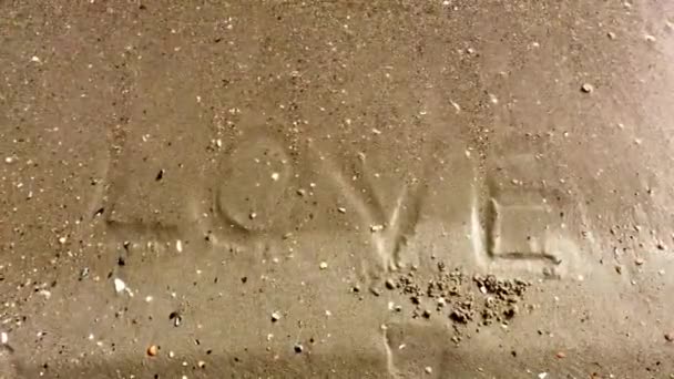 Le onde lavano via l'iscrizione "Love" sulla sabbia — Video Stock