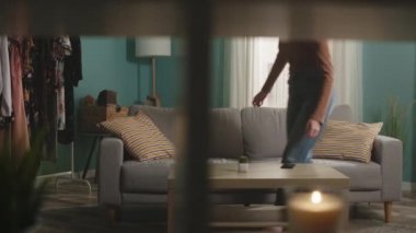 Genç bir kız odaya girer, kanepeye oturur ve telefonu alır.