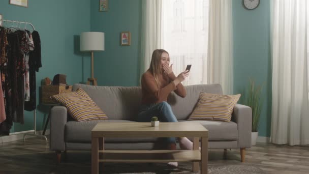 Young lady looks at something on the phone and expresses joyful emotions — Stock Video