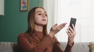 Kız kanepede oturuyor ve bir video görüşmesinde konuşuyor. Yakın plan.