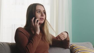 Kız kanepede oturuyor ve telefonda konuşuyor. Yakın plan.