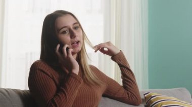Kız kanepede oturuyor ve telefonda konuşuyor. Yakın plan.