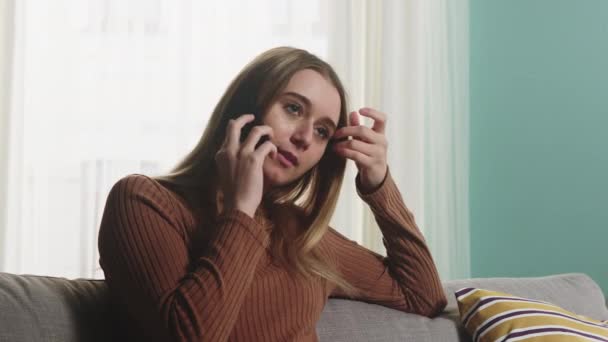 Jong meisje zit op een bank en praat aan de telefoon. Close-up — Stockvideo