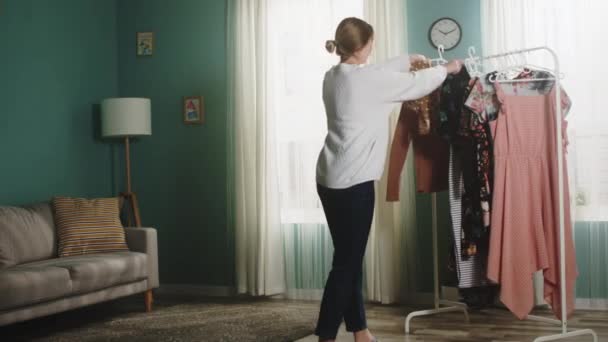 흰 스웨터 를 입은 소녀는 방 주위에 옷을 흩어 놓는다 — 비디오