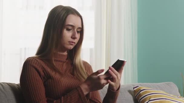 Jong meisje zit op een bank en praat aan de telefoon. Close-up — Stockvideo