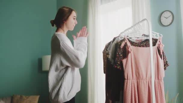 즐거운 감정을 가진 젊은 여자가 옷을 선택 한다 — 비디오