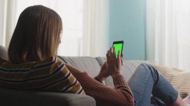 Kız kanepede uzanıyor ve bir video görüşmesinde konuşuyor. Kromakey