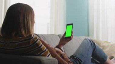 Kız kanepede uzanıyor ve bir video görüşmesinde konuşuyor. Kromakey