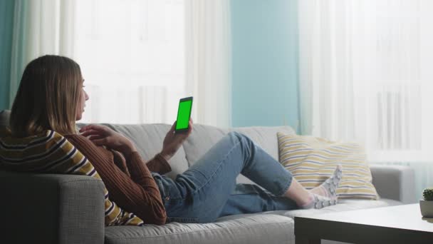 Wanita muda berbaring di sofa krem dan berbicara pada panggilan video. Chromakey — Stok Video