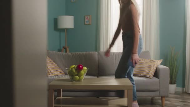 Flickan går in i rummet med telefonen och tar äpplet — Stockvideo