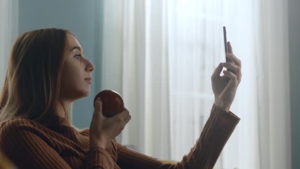 Mooie vrouw met een rode appel neemt een selfie op een mobiele telefoon — Stockvideo